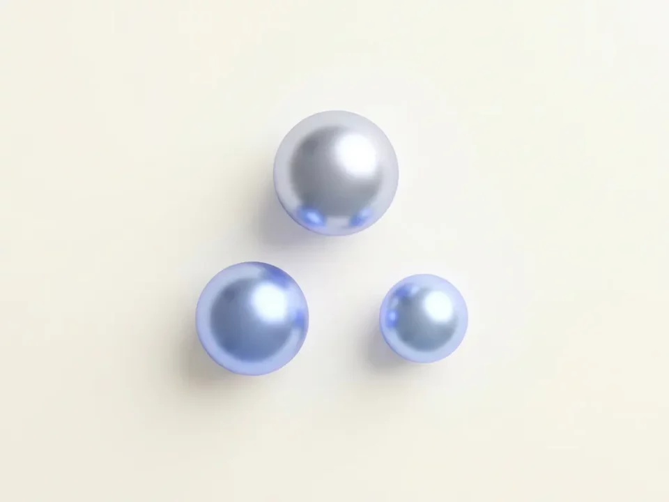 Drie glanzende geometrische bollen in driehoeksformatie op mat wit oppervlak, in zilver en elektrisch blauw met subtiele schaduw.