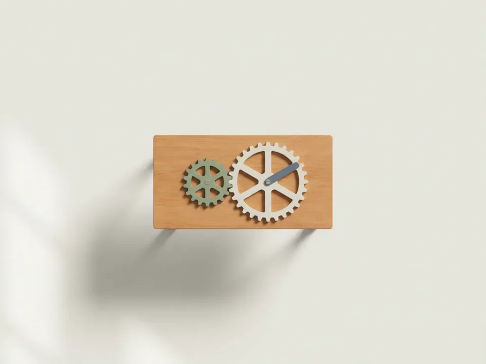 Kleine houten bureau met twee ineengrijpende tandwielen in salie groen en leisteen blauw, bovenaanzicht met zacht natuurlijk licht.